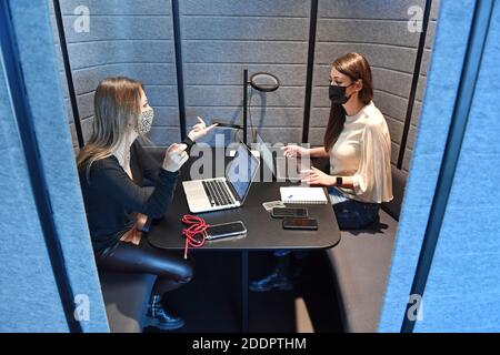 Themenbild Coworking Space: Zwei junge Frauen arbeiten am 22. November 2020 in einem Coworking-Büro an ihren Laptops. Coworking ist eine Entwicklung im Bereich der "neuen Arbeitsformen". Freiberufler, kleinere Startups oder digitale Nomaden arbeiten in meist größeren, relativ offenen Räumen und können so voneinander profitieren. Sie arbeiten entweder selbstständig in verschiedenen Unternehmen und Projekten oder entwickeln gemeinsam mit anderen Mitarbeitern Projekte. MODELL FREIGEGEBEN! Weltweite Nutzung Stockfoto