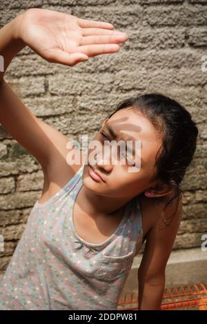 Südostasiatische Ethnizität Teenager-Mädchen im Freien Sonnenbaden am Morgen zu Hause. Hand heben bis zu ihrem Gesicht von harten Sonnenlicht zu decken Stockfoto