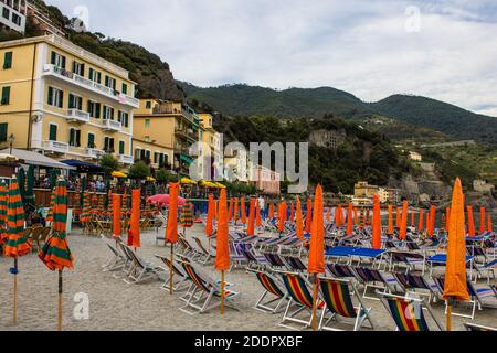 Monterosso al Mare, Italien - 8. Juli 2017: Menschen sitzen in einem Café am Strand von Fegina mit traditionellen bunten Häusern im Hintergrund auf einem Sommer D Stockfoto