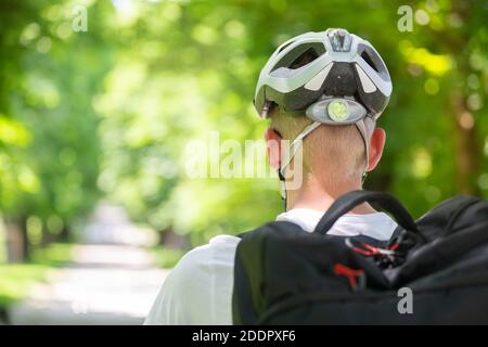 Rückansicht des nicht erkennbaren Mannes, der Schutzhelm auf dem Fahrrad trägt Radfahren im Stadtpark Stockfoto