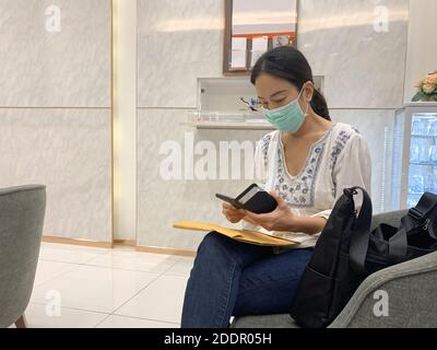 Frau in Schutzmaske mit Smartphone Stockfoto