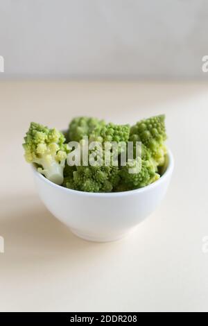 Romanesco Blumenkohl in einer weißen Schale auf hellem Hintergrund. Gesunde Ernährung Konzept. Speicherplatz kopieren. Vertikale Ausrichtung. Stockfoto