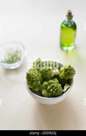 Romanesco Blumenkohl in einer weißen Schale mit Olivenöl auf einem Tisch auf hellem Hintergrund. Gesunde Ernährung Konzept. Selektiver Fokus. Speicherplatz kopieren. Horizontal o Stockfoto