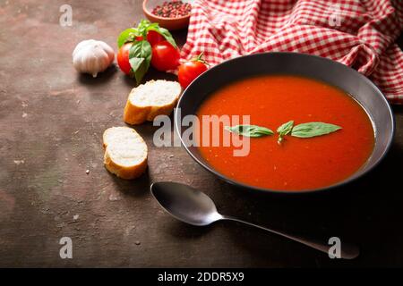 Schüssel Tomatensuppe mit Basilikum und Zutaten zum Kochen Stockfoto