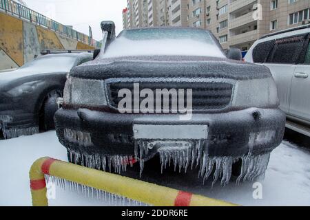 Der schwarze SUV ist eingefroren. Bedeckt mit einer Eiskruste nach dem Regen im Winter. Stockfoto