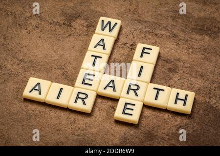 Wasser, Erde, Luft und Feuer Kreuzworträtsel in Elfenbein Buchstaben Fliesen gegen strukturierte handgemachte Papier, vier Elemente der klassischen griechischen Philosophie Stockfoto