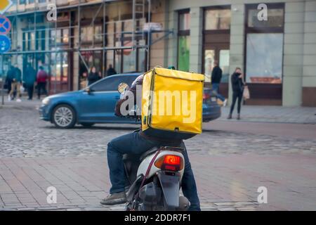 Schnelle Lieferung, Arbeit während der Quarantänezeit, ein Mann auf einem Roller liefert Nahrung für Menschen in Isolation aufgrund Coronavirus. Pandemie Stockfoto