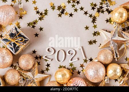 Holznummern 2021 auf einem Papierhintergrund mit glänzenden goldenen Weihnachtskugeln, Glitzersternen aus der Nähe. Wunderschöne Jahreskarte Stockfoto