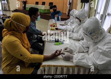 Medan, Nord-Sumatra, Indonesien. November 2020. Ein mit einem Hazmat-Anzug bekleidetes medizinisches Fachpersonal sammelt Blutproben von einer Frau während eines Anti-Körper-Schnelltests auf Coronavirus am 26. November 2020 in Medan. Quelle: Albert Ivan Damanik/ZUMA Wire/Alamy Live News Stockfoto