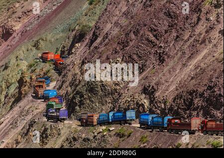 LKWs in einem Stau in einem stecken Unglaublich enge und gefährliche Bergstraße im chinesischen Himalaya Mit buntem Felsen Stockfoto