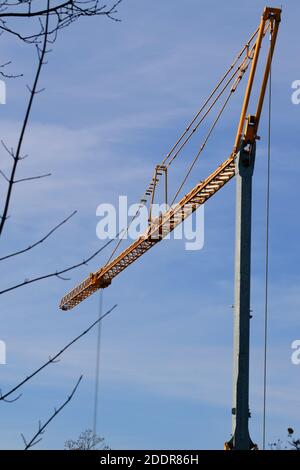 Kran mit gelbem Boom gegen einen blauen Himmel Stockfoto
