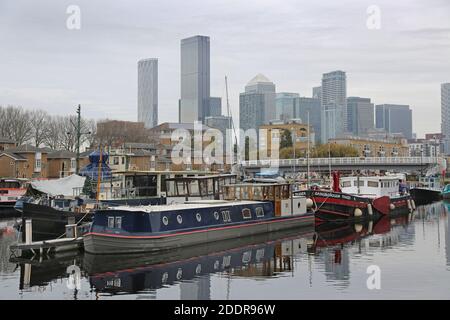 Hausboote in Greenland Dock, Rotherhithe, London, Teil der neu entwickelten Surrey Docks Gegend. Die Türme von Canary Wharf im Hintergrund. Stockfoto