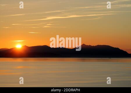 Isle of Arran, Schottland, Großbritannien. Sonnenuntergang über der Insel vom Strand in Ayr. Bekannt als der schlafende Riese aufgrund seiner Umrisse, besonders von der Ayrshire Coast aus gesehen. Stockfoto