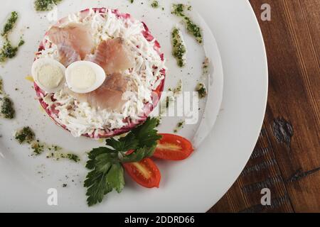 Hering unter Pelzmantel russischer Salat. Holzhintergrund Stockfoto