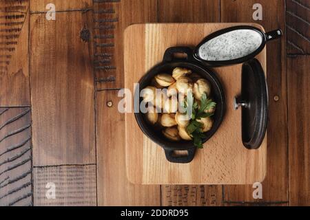 Gebratene Fleischknödel Pelmeni, Chuchpara in einer schwarzen Pfanne. Holzhintergrund. Stockfoto