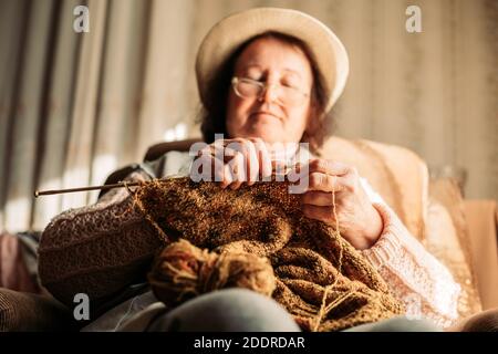 Ältere Frau Strickpullover für ihre Enkelkinder. Konzentrieren Sie sich auf die Nadeln Stockfoto