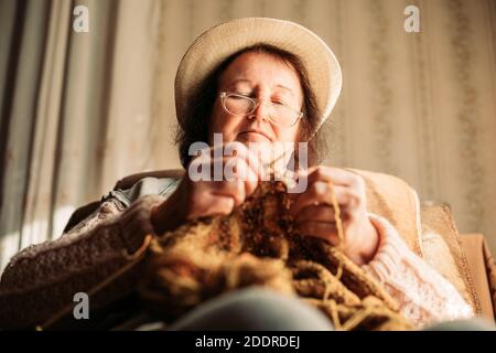 Ältere Frau Strickpullover für ihre Enkelkinder. Fokus auf das Gesicht Stockfoto