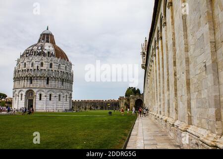 Pisa, Italien - 9. Juli 2017: Blick auf Touristen, Baptisterium San Giovanni und Campo Santo (monumentaler Friedhof) auf der Piazza dei Miracoli Stockfoto