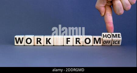 Arbeiten Sie von zu Hause aus. Die Hand dreht Würfel und ändert die Wörter „Arbeit vom Büro“ in „Arbeit vom Büro“. Schöner grauer Hintergrund. Business und covid-19 Pandemie Stockfoto