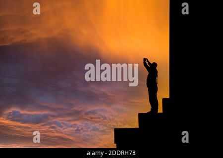 Mann, der beim Sonnenaufgang ein Foto vom National Monument of Scotland auf Calton Hill unter einem atemberaubenden Himmel gemacht hat. Edinburgh, Schottland. VEREINIGTES KÖNIGREICH Stockfoto