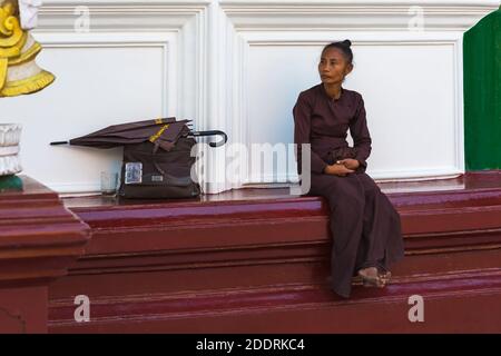 Frau mit Regenschirm und Tasche, die im Februar in der Shwedagon Pagode, Yangon, Myanmar (Burma), Asien sitzt Stockfoto