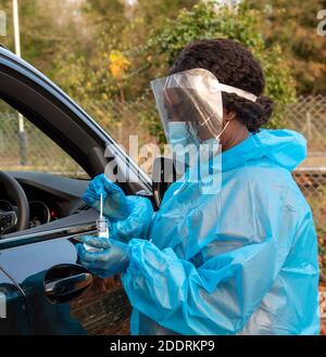 Südengland, Großbritannien. 2020. Schwarzer Tester im Covid-19 Testzentrum, der Tupfer in einen Plastikbehälter legt, nachdem er einen Klienten getestet hat. Stockfoto