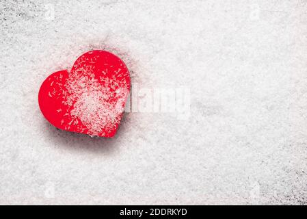 Rotes Herz von Schnee bedeckt, Konzept Bild über Liebe, Romantik, Scheidung, Valentinstag. Platz für Text, Layout, Draufsicht Stockfoto
