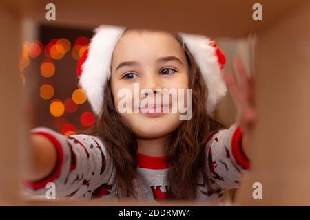 Happy girl in Silvester Pyjamas und Weihnachtsmann Hut Nimmt ein Geschenk Stockfoto