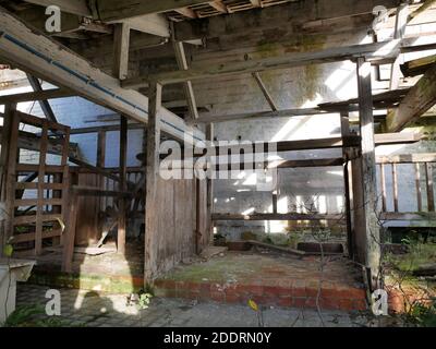 Im Inneren alten baufälligen Bauernhof Kuhstall Gebäude weiß getünchte Wände Stein und Ziegel Boden Holz Trennwände und Dachsparren Stockfoto