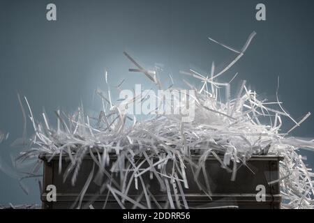 Geschreddert Papierstreifen scheinen in einer Box und explodieren Erweitern Sie ihr Volumen, das über den Rand des Kastens verschüttet wird Stockfoto