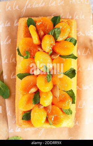 Orange Pound Cake mit frisch gepresstem Orangensaft und Orangenschale, dekoriert mit getrockneten Aprikosen, Minzblättern und Mandeln. Stockfoto
