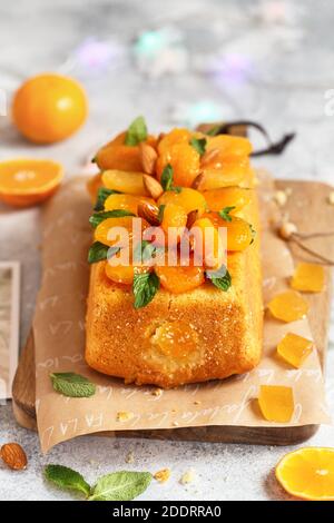 Orange Pound Cake mit frisch gepresstem Orangensaft und Orangenschale, dekoriert mit getrockneten Aprikosen, Minzblättern und Mandeln. Stockfoto
