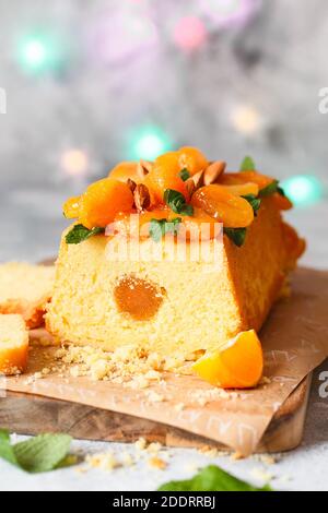 Orange Pound Cake mit frisch gepresstem Orangensaft und Orangenschale, dekoriert mit getrockneten Aprikosen, Minzblättern und Mandeln. Stockfoto