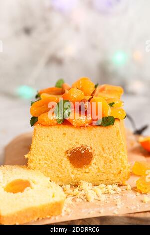 Orange Pound Cake mit frisch gepresstem Orangensaft und Orangenschale, dekoriert mit getrockneten Aprikosen, Minzblättern und Mandeln. Stockfoto
