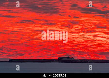 Charmouth, Dorset, Großbritannien. November 2020. Ein spektakulärer feuerroter Sonnenuntergang über dem Cobb Harbour und Lyme Regis in Dorset vom Strand in Charmouth am Ende eines sonnigen Tages gesehen Bildquelle: Graham Hunt/Alamy Live News Stockfoto