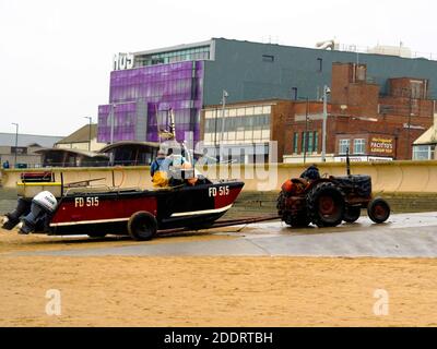 Fischer schleppt sein Boot FD515 Unsere Vallerie Ann den Slipway mit seinem Kumpel auf dem Anhänger vom Strand auf die Straße Redcar Cleveland UK , Stockfoto