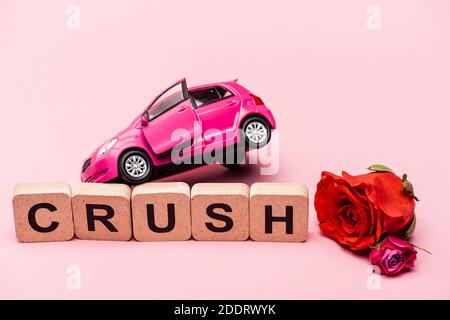 rosen, Spielzeugauto und Wort Crush auf Würfel auf rosa Hintergrund Stockfoto