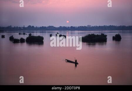 31.01.2010, Muang Khong, Laos, Asien - Blick von der Don det Insel auf ein hölzernes Kanu, das gegen den Sonnenaufgang über dem Mekong River silhouettiert ist. Stockfoto