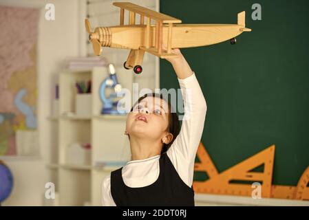 Träumen Sie weiter. Schulmädchen spielen Holz Spielzeug Flugzeug. Fliegen Sie im Flugzeug. Studium der Geographie. Weltweit. Träume vom Reisen. Zurück zur Schule. Geschichte über Sommerferien. Wie ich den Sommer verbrachte. Anreise mit dem Flugzeug. Stockfoto