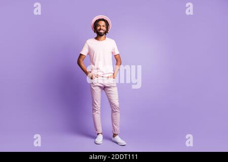 Foto von jungen afro gut aussehend fröhlich gute Laune positiven Mann Männlich Kerl posiert halten Hände in Taschen isoliert auf violett Farbiger Hintergrund Stockfoto