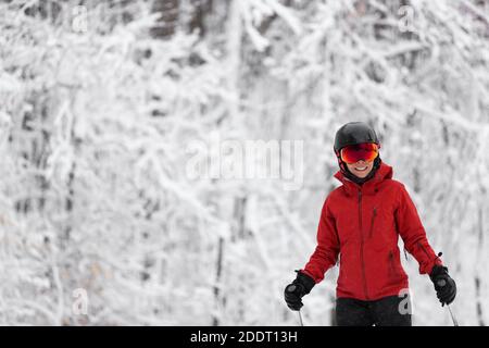 Wintersport glücklich Skifahrer Alpine Skifahren gehen dowhill gegen schneebedeckten Bäumen Hintergrund während Winter Schneesturm. Frau in roter Jacke und Brille Stockfoto