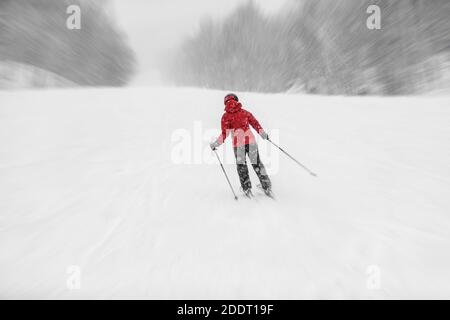 Skifahren Alpinski während des Schneesturms. Frau Athlet Reiten schneebedeckten Hang bei kaltem Wetter whiteout. Winter Snowsport Stockfoto