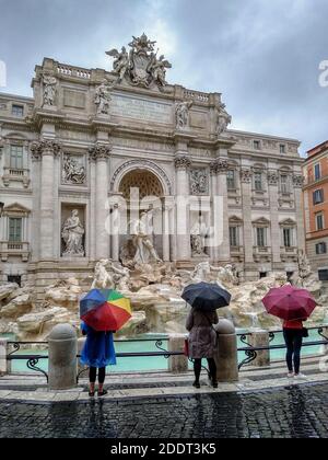 Touristen mit bunten Sonnenschirmen vor dem Trevi-Brunnen - wenige Menschen an einem regnerischen Tag - Rom, Italien Stockfoto