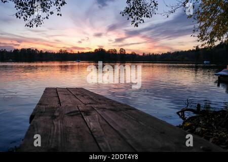 Hölzerne Pier auf dem See bei Sonnenuntergang spiegelt sich in der Gewässer Stockfoto