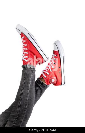 Beine einer jungen Frau in stylischen roten Sneakers auf weißem Hintergrund. Stockfoto