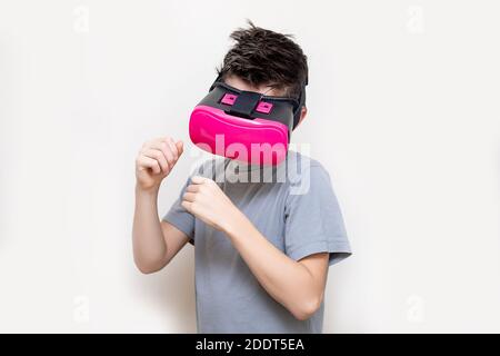 Happy teen junge tragen virtuelle Realität beobachten studieren Filme oder spielen Videospiele, Studio erschossen. Fröhlicher Teenager in rosa VR-Brille suchen. Spaß Stockfoto