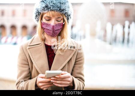 Addicted Frau mit Schutzmasken mit Tracking-App auf Handy Smartphone - Junge besorgt Millennial-Sharing-Inhalte auf Social Media Stockfoto