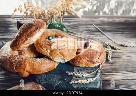 Hausgemachte Brezeln, Bagels und Brötchen in einer Papiertüte auf einem dunklen Holztisch. Handgebackenes Brot aus nächster Nähe. Umweltfreundliche wiederverwendbare Verpackung. Stockfoto