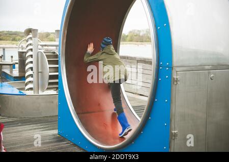 Teen Junge läuft in einem Rad auf Spielplatz in Skandinavien In der Nähe des Meeres Stockfoto