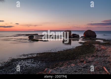 Schöner, farbenfroher Sonnenuntergang über Meer und Felsen. Ostsee. Estland. Langzeitbelichtung. Stockfoto